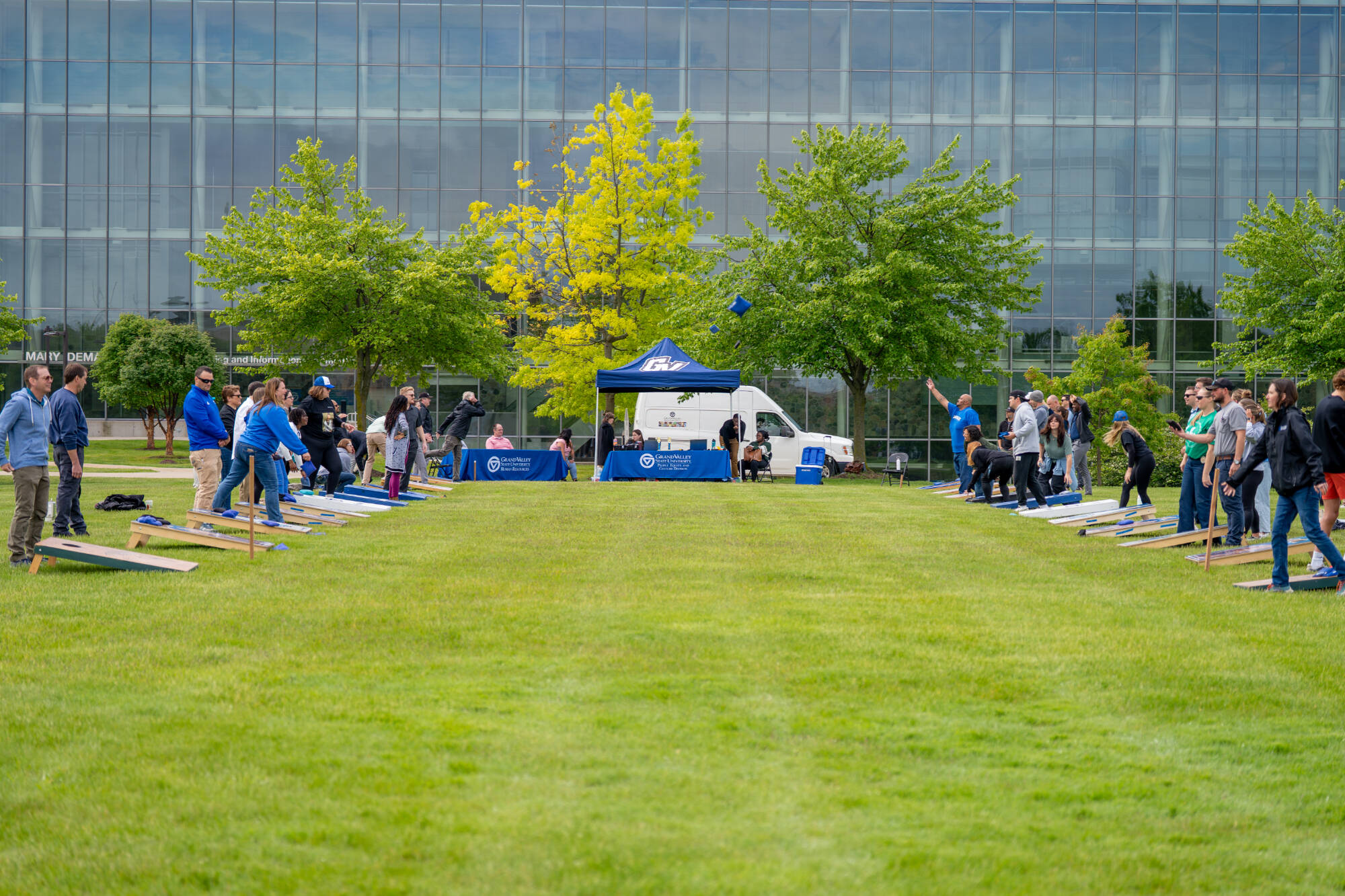 wide view of GVSU cornhole tournament, bags being thrown during multiple games across the Mary Idema Pew Library lawn